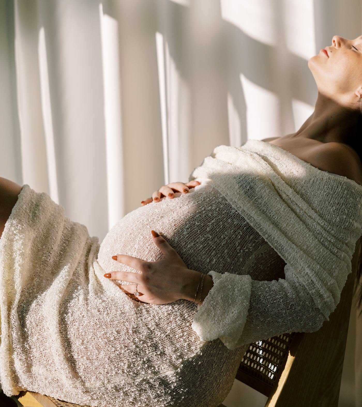 Soft sunlit portrait of a pregnant woman reclining in warm window light.